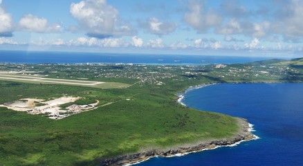 Fototapeta na wymiar Aerial view of Saipan International Airport runway and Lau Lau Bay seen from the window of an airplane 