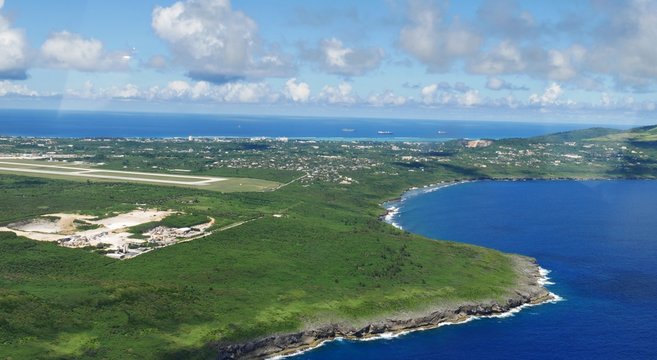 Fototapeta Aerial view of Saipan International Airport runway and Lau Lau Bay seen from the window of an airplane 
