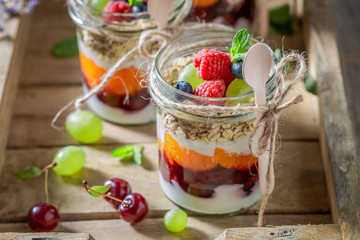 Sweet oat flakes with fresh fruits and yoghurt in jar