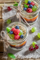 Tasty oat flakes with fresh fruits and yoghurt in jar
