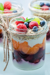 Granola in jar with yoghurt and berry fruits on white