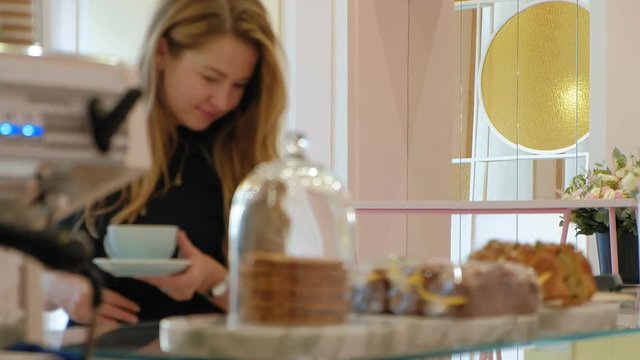 She buyer chooses yummy. Young attractive girl, woman buys in the coffee shop or pastries, cakes, cake, macaroon. A buyer standing under a a glass case at the bakery, coffee shop
