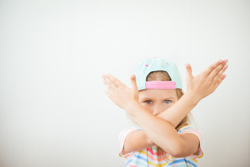 Serious girl making stop sign with crossed hands against white background in studio, copy space
