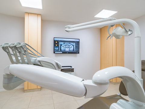 Clean white modern dentist cabinet. Spacious room with a dental radiography on a screen