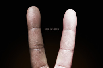 Photography idea showing a black and white finger making a peace sign against racism.