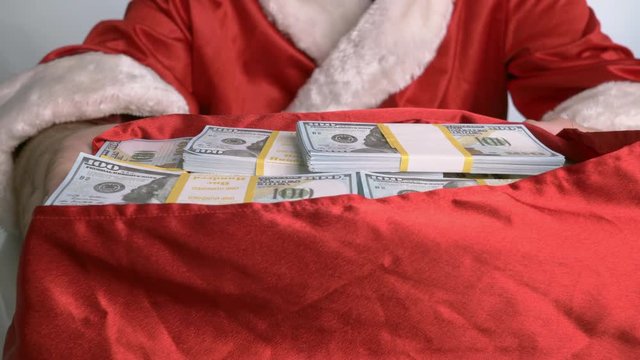 Santa Claus moves the bag of money from himself to the viewer.