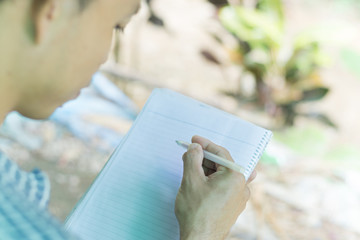 The young man is writing a new idea on the notebook.