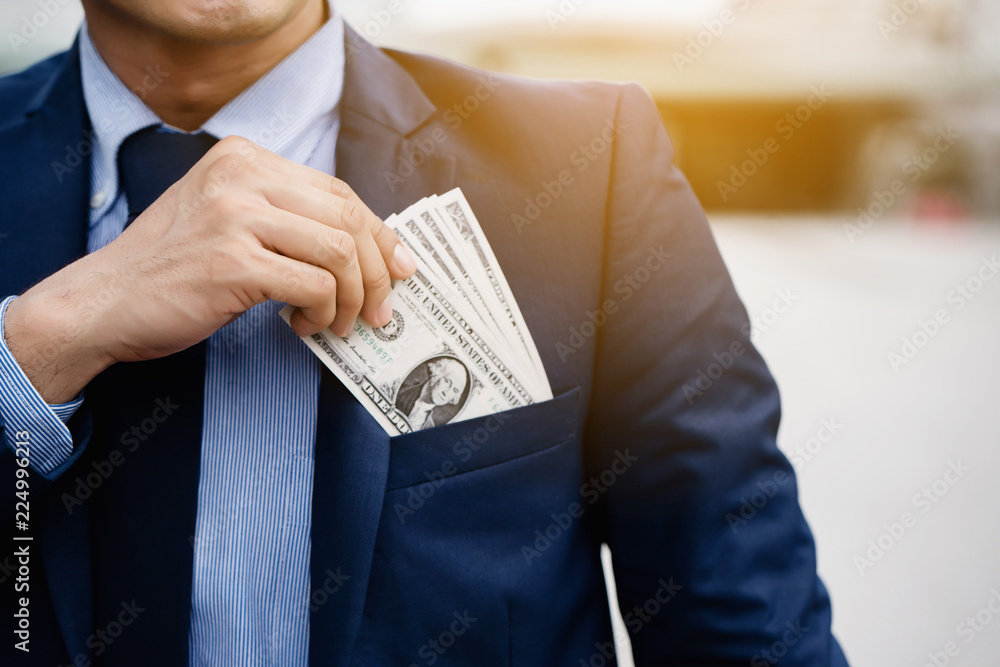 Poster Close up hand of a businessman holding banknote into pocket. It represents very profitable investment. The exchange of currencies with good returns. And money to buy debt securities increase revenue.