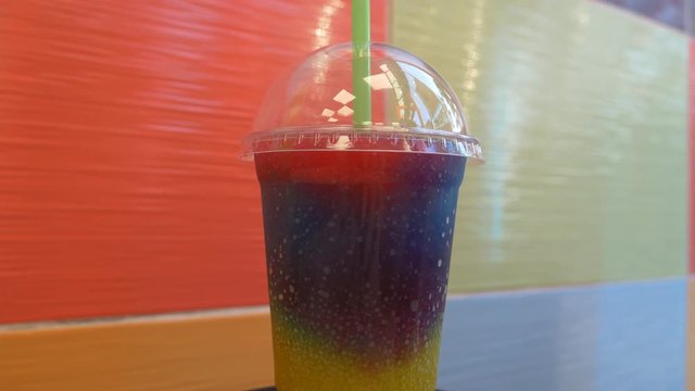 A cup of colourful slushy drink on the table.