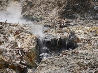 Medium close up shot of up a small crater with smoke rising out of the drive-thru volcano at the Sulphur Springs in St Lucia, Caribbean Islands
