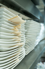 Obraz na płótnie Canvas endless row of white ceramic dinner plates and napkins neatly stacked on a metal shelf in a restaurant kitchen