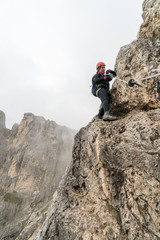 young attractive female mountain climber on a steep and exposed Via Ferrata in Alta Badia in the...