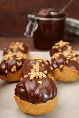 Eclairs with chocolate and nuts on wooden background