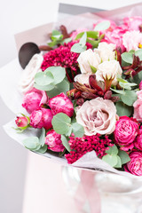 beautiful spring bouquet. flowers arrangement with various of colors in glass vase on pink table. bright room, white wall
