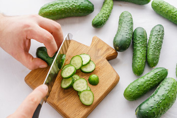 Mans hands cutting cucumbers for detox water. Top view. Process of preparing energy cocktail