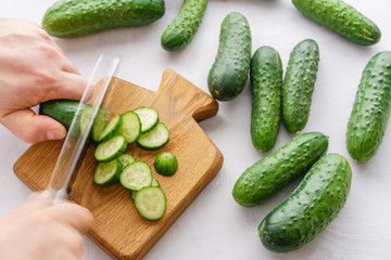 Mans hands cutting cucumbers for detox water. Top view. Process of preparing energy cocktail