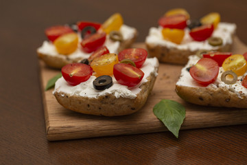 Sandwich with cottage cheese, tomatoes, olives and Basil on wooden background