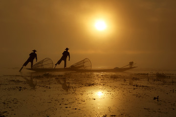 Silhouette of traditional fisherman in wooden boat on Inle lake with fog sunrise , Myanmar