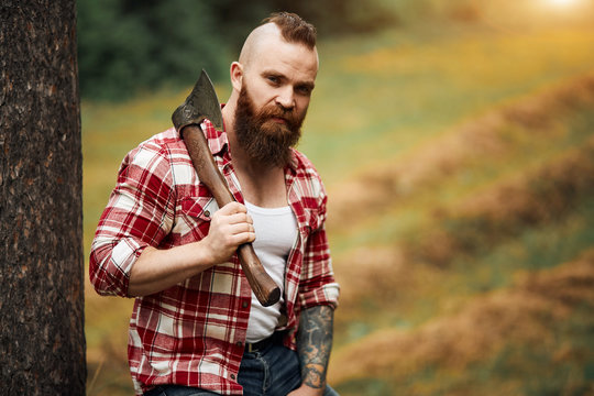 Portrait of bearded woodcutter man with axe outdoor landscape background