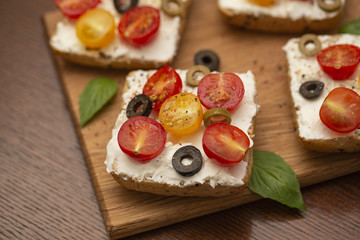 Sandwich with cottage cheese, tomatoes, olives and Basil on wooden background