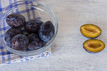 Harvested Fresh blue plums at light wooden background/ Food background/ Flatware