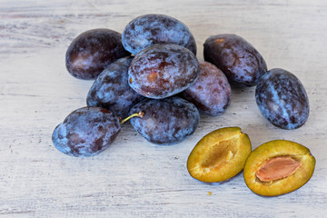 Harvested Fresh blue plums at light wooden background/ Food background/ Flatware