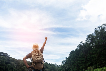 Happy hiker man with backpack with raised hand. sky and forest background. Concept of success.