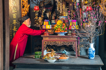 Old Vietnamese man preparing altar with foods for the last meal of year. The penultimate New Years Eve - Tat Nien, the meal finishing the entire year. Vietnam lunar new year.