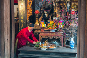 Old Vietnamese man preparing altar with foods for the last meal of year. The penultimate New Years...