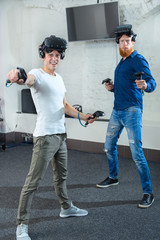 Two young guys are playing in a shooter, in virtual reality glasses