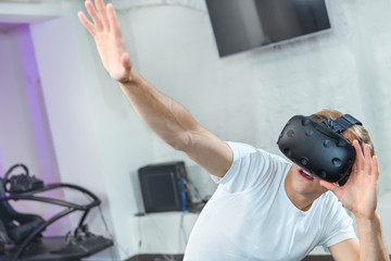 A young guy in a white T-shirt plays virtual reality games