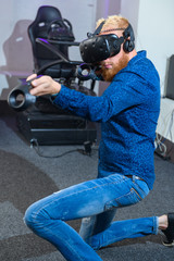 A young, handsome guy, in a blue sports suit, with a red beard, playing virtual reality games