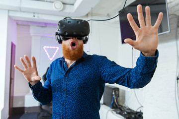 A young, handsome guy, in a blue sports suit, with a red beard, playing virtual reality games