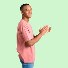 Dark skinned man applauding after presentation in a conference on green isolated background