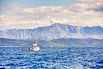 Beautiful sea landscape, sailboat sailing on the distance on great majestic mountains background, romantic cruise in the Adriatic sea, Croatia