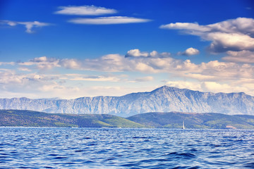 Beautiful sea landscape, sailboat sailing on the distance on great majestic mountains background, romantic cruise in the Adriatic sea, Croatia