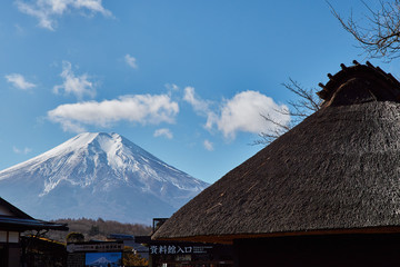 冬の日本の富士山とわらぶき屋根の古民家