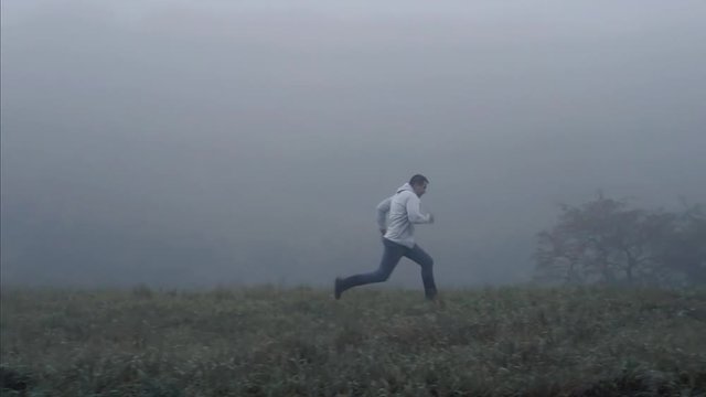 Man running on the grass in the fog,slow mo