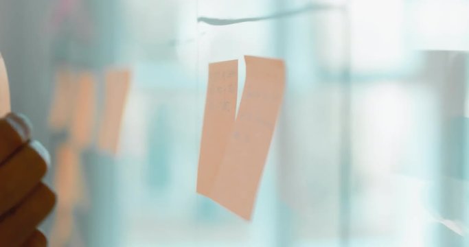 African American black employee looking onto a glass wall with sticky notes, framework for managing work, scrum methodology. 4K UHD 60 FPS SLOW MOTION