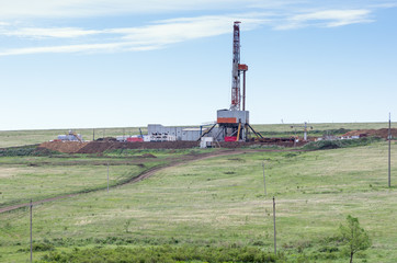 Fototapeta na wymiar Drilling tower in the steppe. Steppe landscape with drilling rigs and equipment