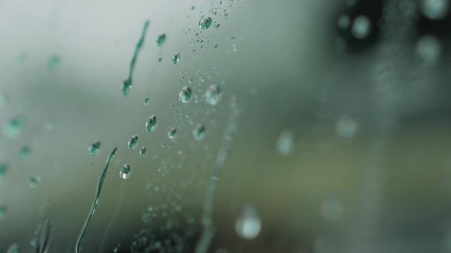 Slow motion handheld water drop sliding from car glass