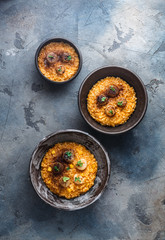 Three risotto bowl on stone background, top view