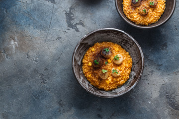 Risotto with pumpkin and scallops, on stone background, copy space