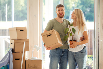 Smiling couple hold boxes in new home. Dreaming new home