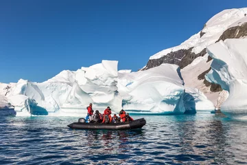 Foto auf Acrylglas Antarktis Ein Boot voller Touristen erkundet riesige Eisberge, die in der Bucht treiben