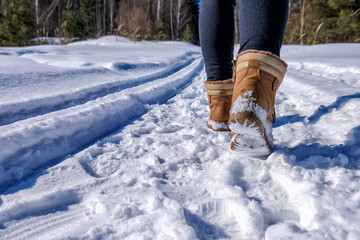 the girl walks on a snow-covered forest path in a sunny frosty day