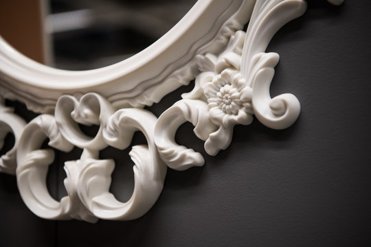 Expensive interior. Stucco elements on a mirror. White patterned. Mouldings element from gypsum or plastic. Roccoco style