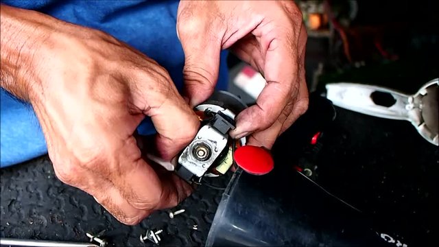 Close up video of the hands of an electrician fixing an electronic household item in his shop.
