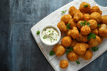 Homemade Breaded Garlic Mushrooms with sour cream and parsley on white wooden board
