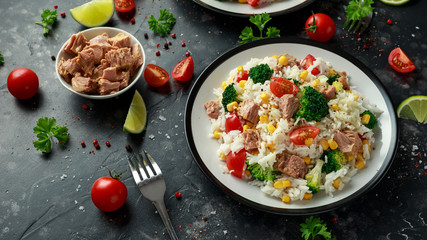 Fresh Tuna rice salad with sweet corn, cherry tomatoes, broccoli, parsley and lime in black bowl
